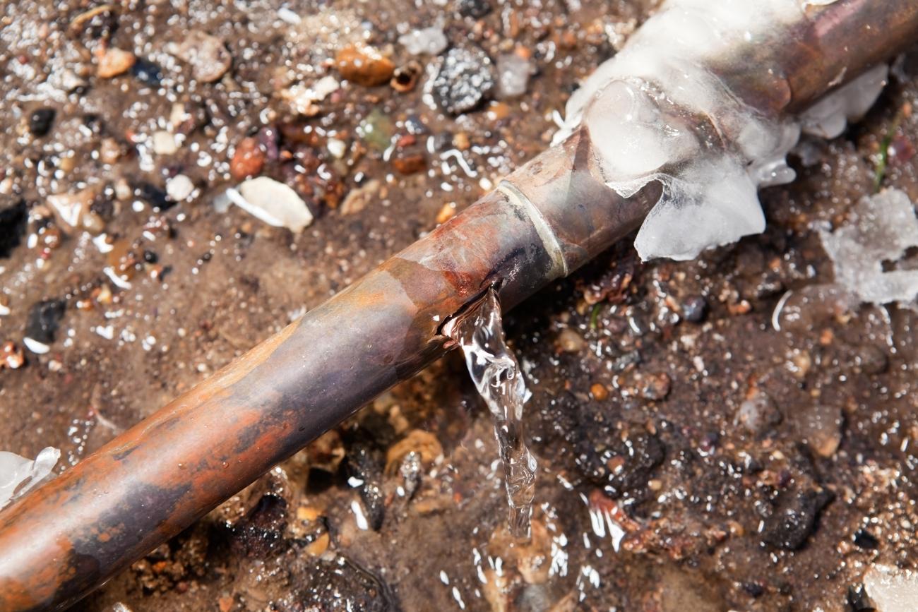A copper pipe covered in ice and leaking