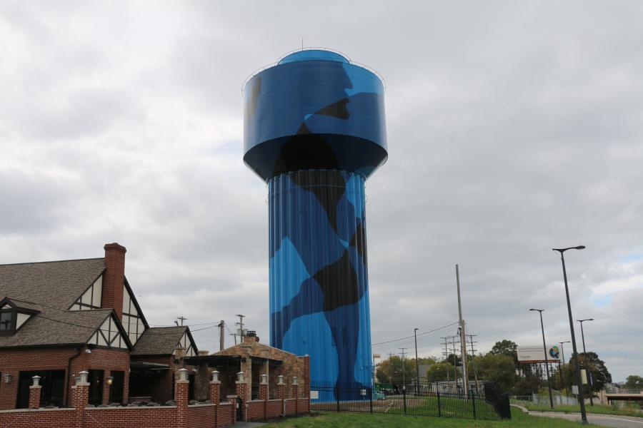A water tower painted with an abstract image in varying blue shade