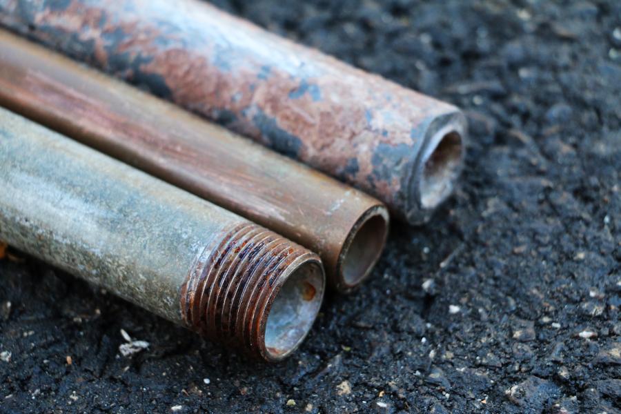 Sections of a galvanized steel water pipe, a copper water pipe, and a lead water pipe laying next to each other