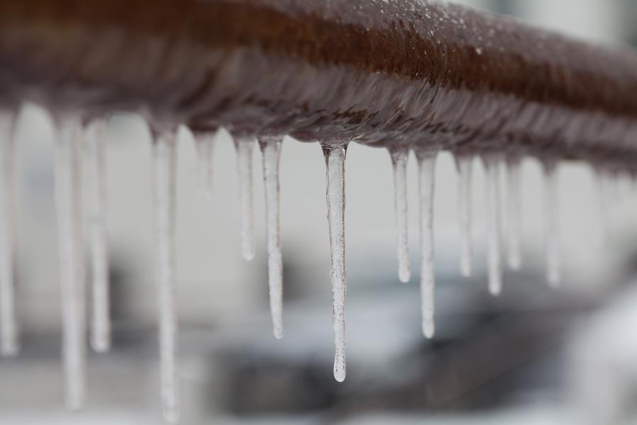 Close up of a copper pipe with icicles hanging from it