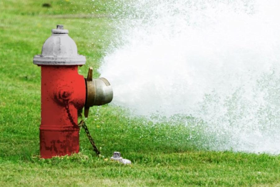 A red fire hydrant with water gushing from it