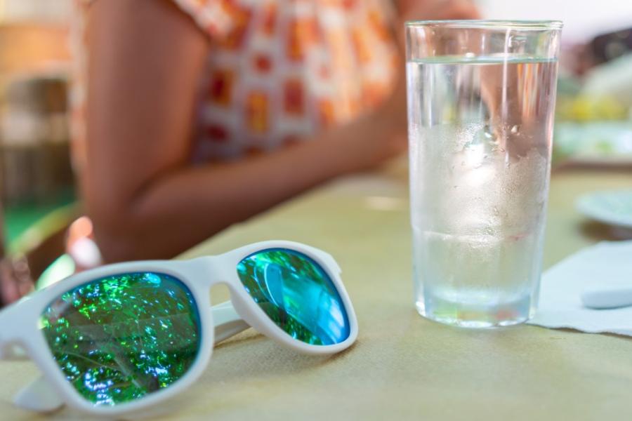 Sunglasses and a glass of water sit on a table at a family barbecue