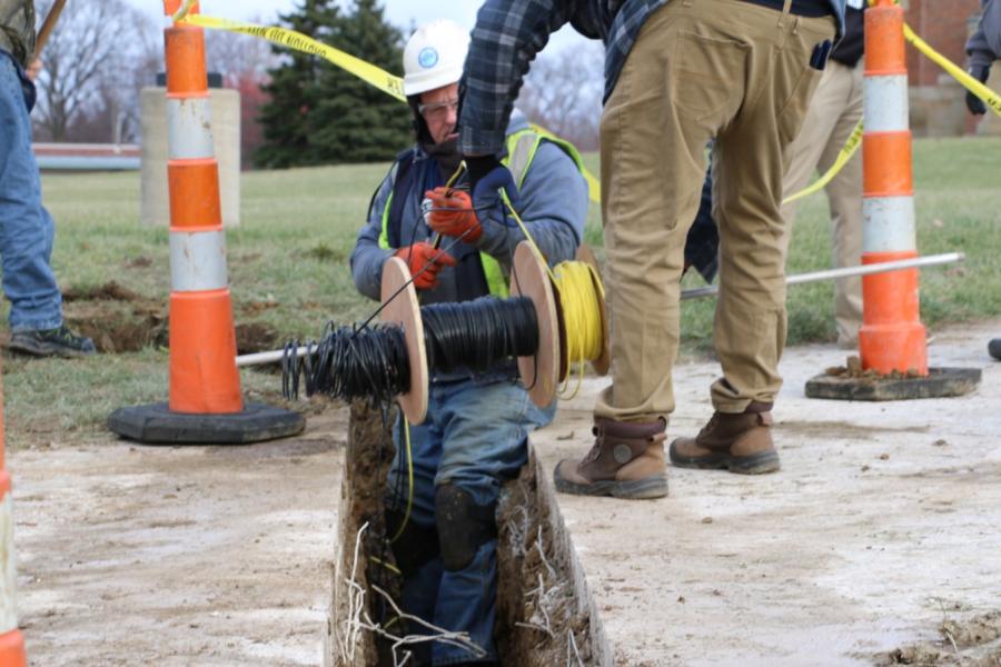 Cleveland Water employees unspool a line of temperature sensors to install in a trench