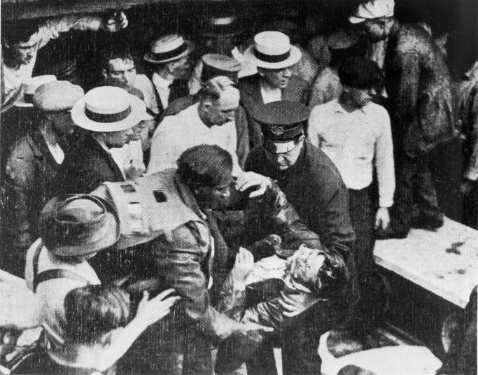 A black and white photo of men crowded around Garrett Morgan holding a rescued tunnel worker