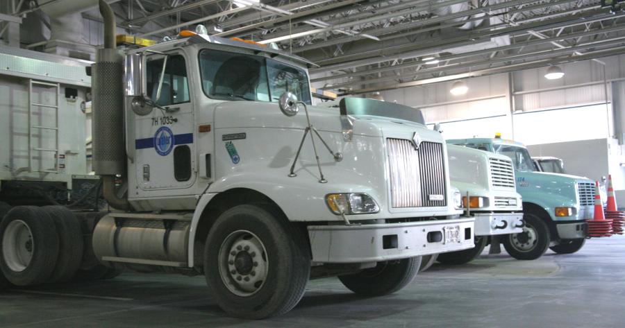 Three large Cleveland Water trucks sit in a row inside a garage