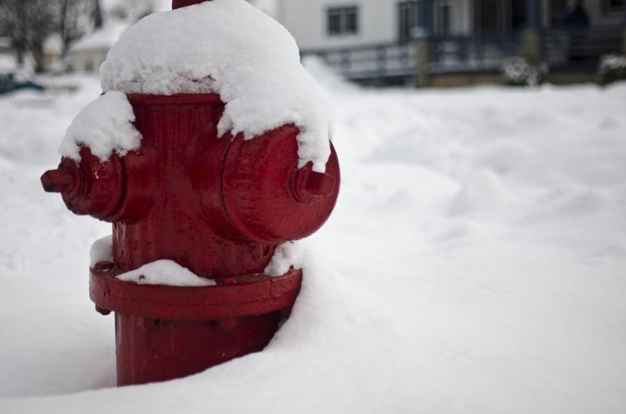 A red fire hydrant covered almost entirely by snow