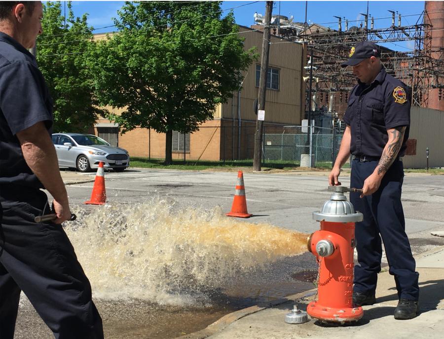 A firefighter opens a hydrant and wash rushes out