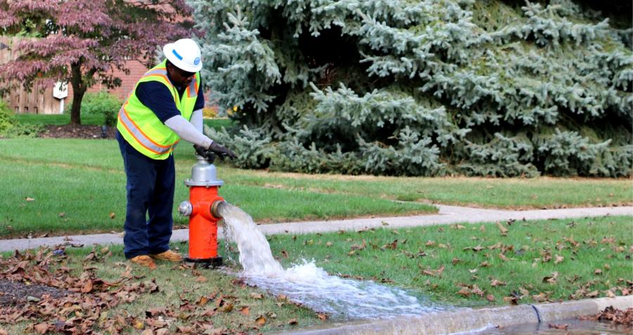 A Cleveland Water worker opens an orange hydrant on a residential street