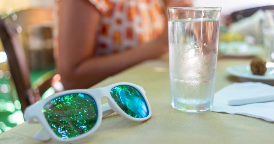 Sunglasses and a glass of water sit on a table at a family barbecue